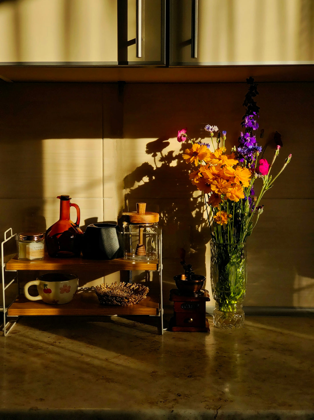 Flowers and coffee accessories sit in sunlit kitchen