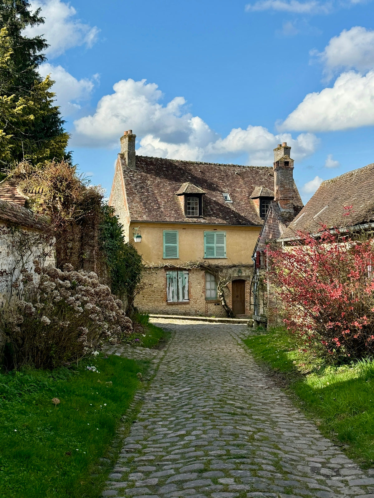 Rustic yellow house with blue shutters and a cobblestone path