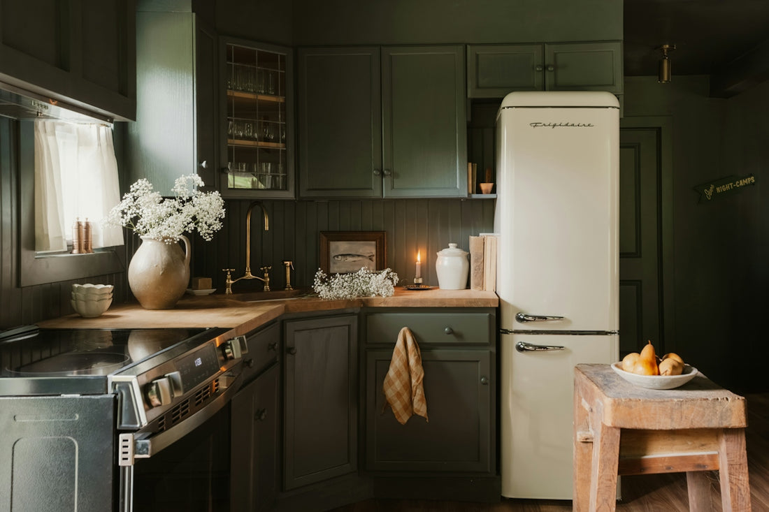 A dark green kitchen with a cream refrigerator and wooden countertops