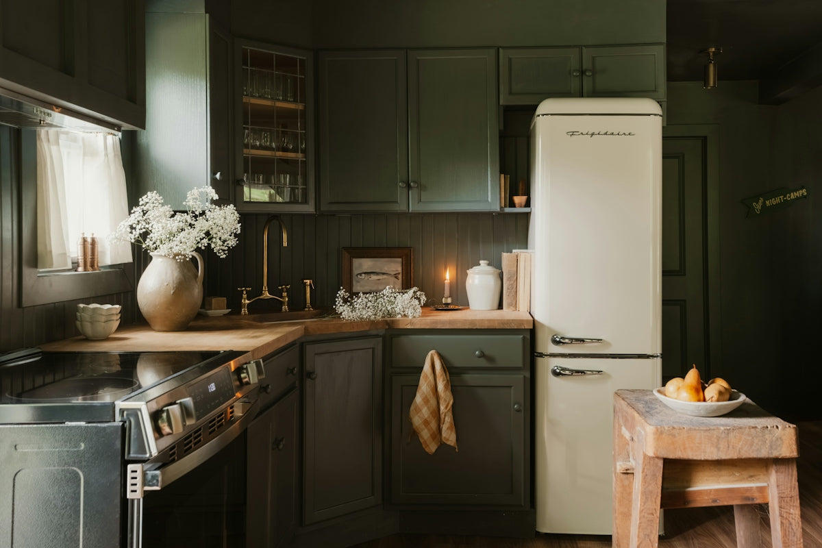 A dark green kitchen with a cream refrigerator and wooden countertops
